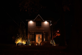 Outdoor Christmas light installation on a home in Vaughan with roofline and trees decorated in glowing lights